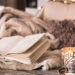 Cosy winter setting with cups, books, candles, and blankets for a warm and inviting home atmosphere