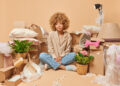 Thoughtful woman surrounded by boxes while decluttering her home, focusing on rubbish clearance and organisation