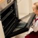 Young girl looking into an open oven before her school