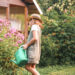 Woman watering flowers in a tidy, blooming garden on a sunny day, with no wasps in sight.