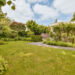 Tidy garden with trimmed hedges and neat lawn under a bright August sky.