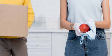 A tenant cleaning a kitchen and bathroom thoroughly before moving out, with cleaning supplies and cloths visible, preparing the property for handover.