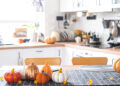 A sparkling UK kitchen after an autumn deep clean, with tidy cupboards, a gleaming oven, and seasonal touches like pumpkins on the counter.
