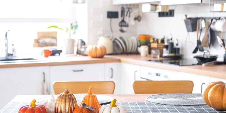 A sparkling UK kitchen after an autumn deep clean, with tidy cupboards, a gleaming oven, and seasonal touches like pumpkins on the counter.