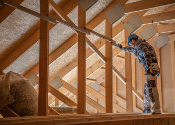 A UK loft with newly installed insulation rolls between wooden joists, helping to keep the home warm and reduce winter heating bills.