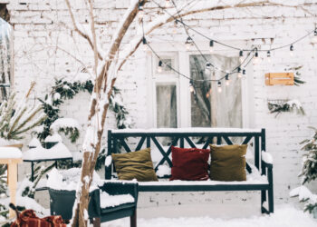 Covered garden furniture and a BBQ set neatly stored on a patio before winter.