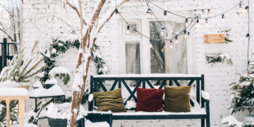 Covered garden furniture and a BBQ set neatly stored on a patio before winter.