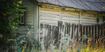 A well-maintained wooden fence and garden shed secured before a storm, surrounded by tidy greenery under a cloudy UK sky.