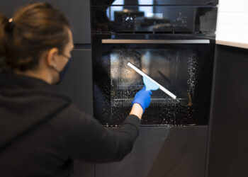 Clean oven in a modern UK kitchen with a packed suitcase nearby, highlighting the importance of oven cleaning before going on holiday.