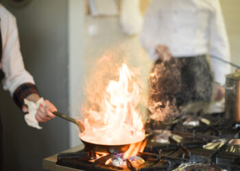 Grease buildup on a kitchen hob and splashback during winter cooking, showing stubborn residue that is harder to remove in colder temperatures.
