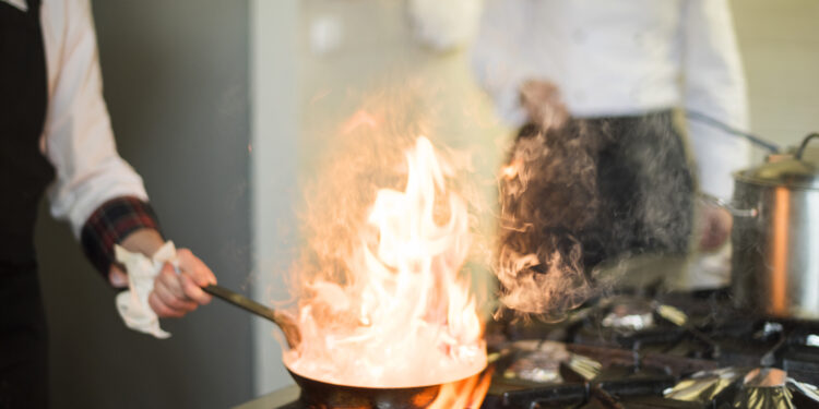 Grease buildup on a kitchen hob and splashback during winter cooking, showing stubborn residue that is harder to remove in colder temperatures.