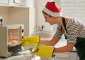 Person cleaning the inside of a microwave in winter, wiping food splatters and steam residue from the interior.