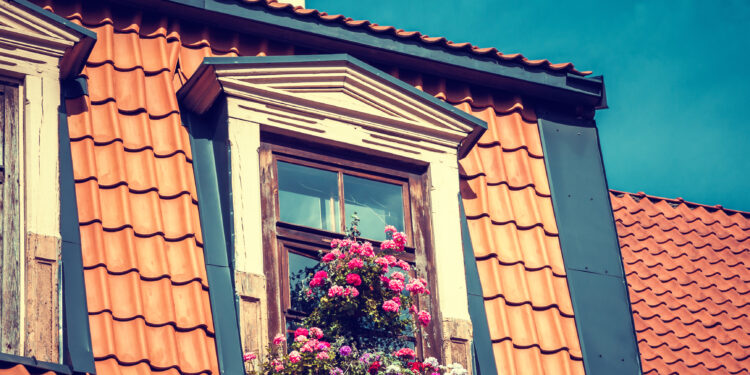 Professional window cleaner using safety equipment to clean upstairs windows on a residential property.