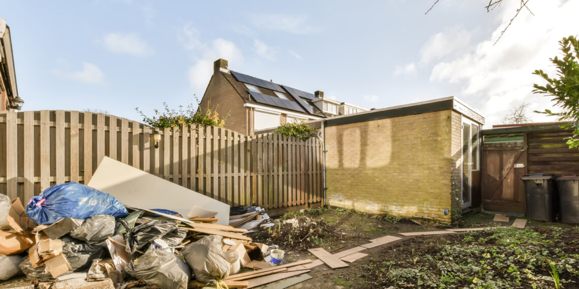 Backyard with a pile of household and construction waste awaiting rubbish clearance in a UK garden