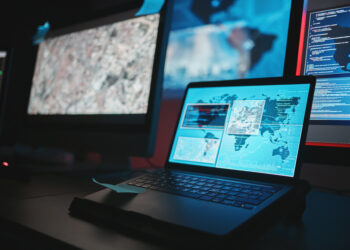 Laptop displaying digital maps and code on multiple screens, representing an online home services platform connecting users with professionals.