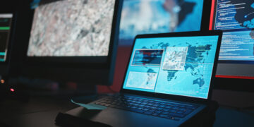 Laptop displaying digital maps and code on multiple screens, representing an online home services platform connecting users with professionals.