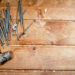 Close-up of a squeaky floorboard being fixed through carpet using a specialised repair screw tool, with the carpet intact.