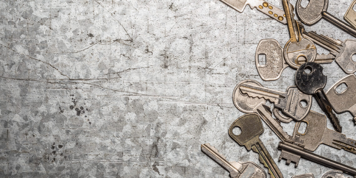 Collection of assorted old metal keys scattered on a textured surface, symbolising outdated or multiple key access