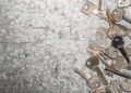 Collection of assorted old metal keys scattered on a textured surface, symbolising outdated or multiple key access