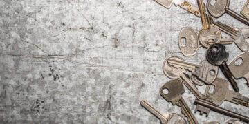 Collection of assorted old metal keys scattered on a textured surface, symbolising outdated or multiple key access