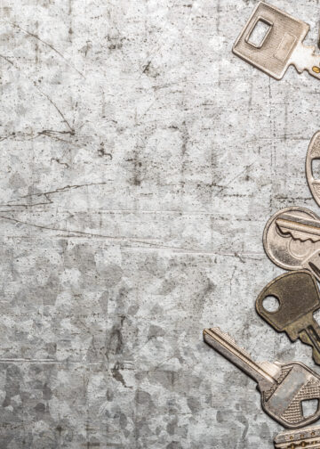 Collection of assorted old metal keys scattered on a textured surface, symbolising outdated or multiple key access