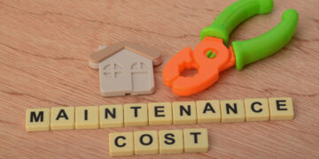 Tools and house model with maintenance cost text representing seasonal home maintenance checklist for UK homeowners