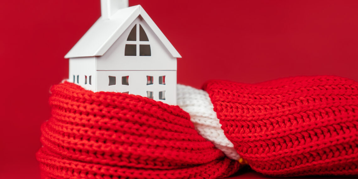 Model house wrapped in a red scarf symbolising home insulation and energy efficiency in UK homes