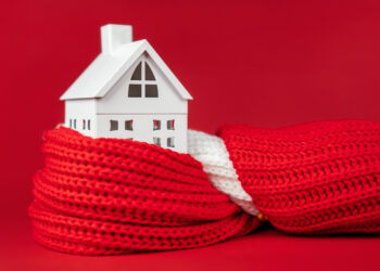 Model house wrapped in a red scarf symbolising home insulation and energy efficiency in UK homes