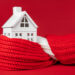 Model house wrapped in a red scarf symbolising home insulation and energy efficiency in UK homes
