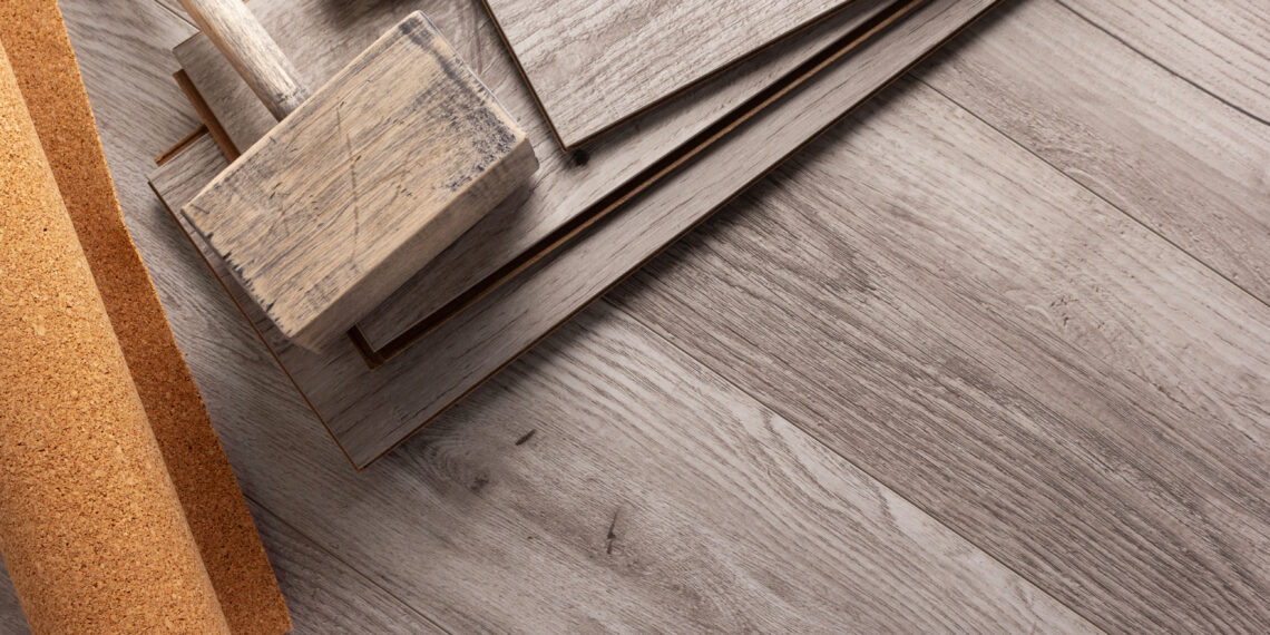 Samples of laminate, vinyl and hardwood flooring planks displayed on wooden floor for UK home renovation comparison