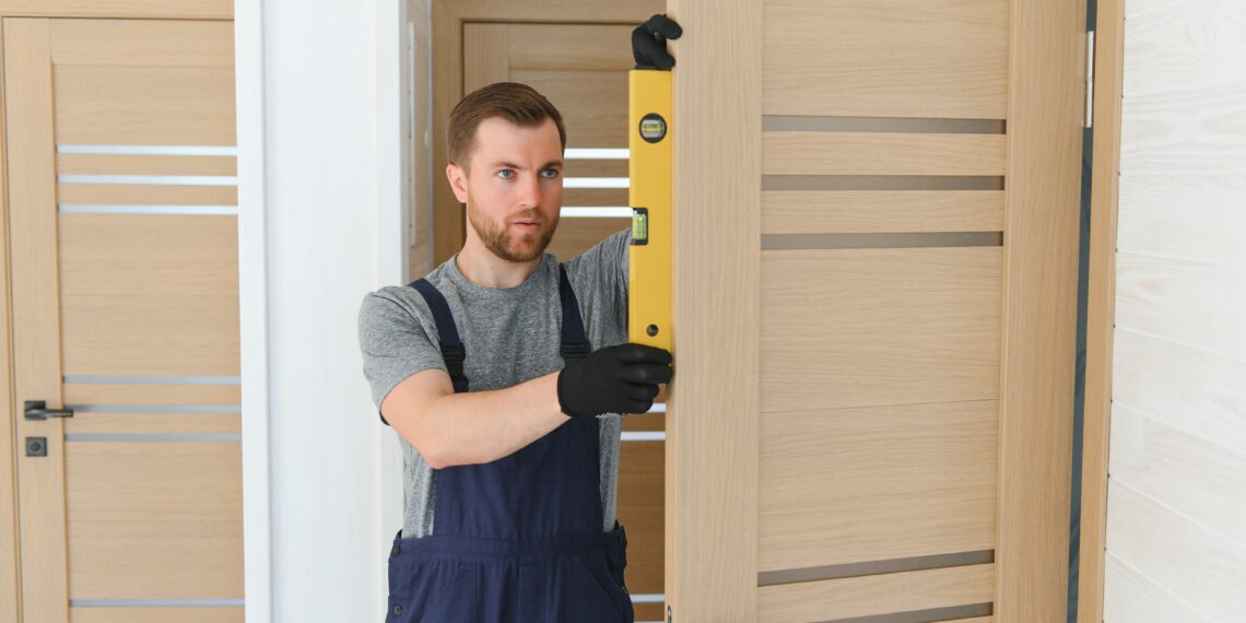 Close-up of a misaligned interior door scraping against the frame, with visible uneven gaps and a hand adjusting the hinge with a screwdriver.