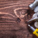A handyman using a drill to assemble wooden furniture in a modern living room while unpacked boxes and tools are spread across the floor.