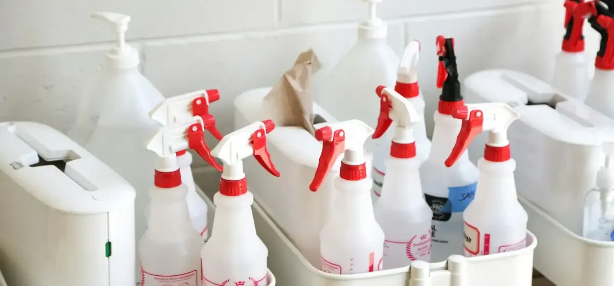 White spray bottles of cleaning product in a plastic caddy