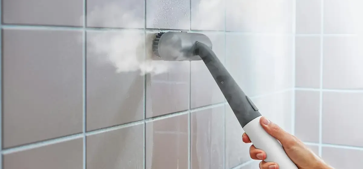 Steam cleaner being used on a tiled bathroom wall