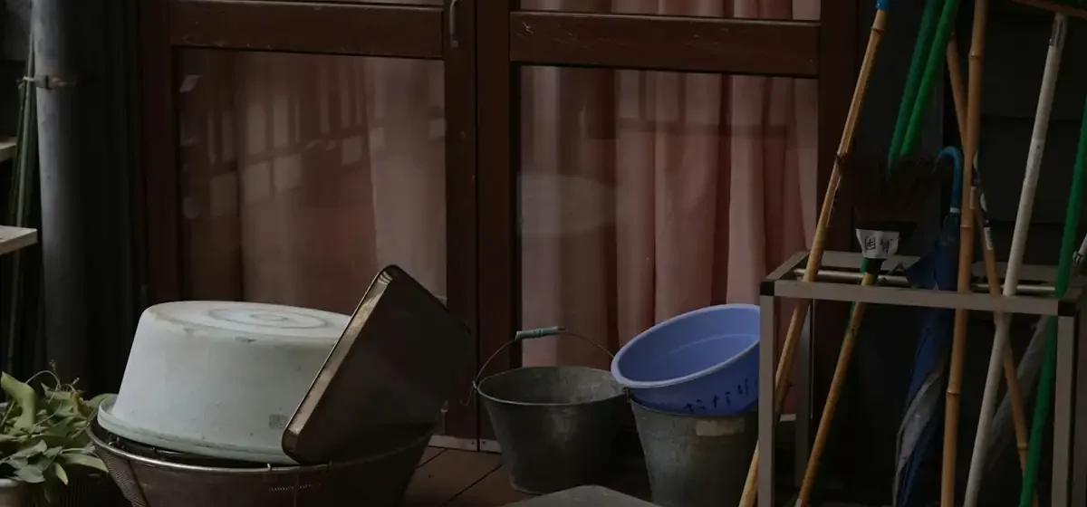 Buckets, brooms and a metal basket on a wooden deck