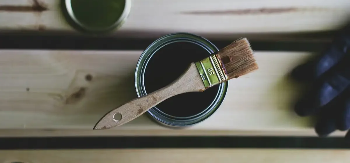 Tin of green paint with a brush resting on top