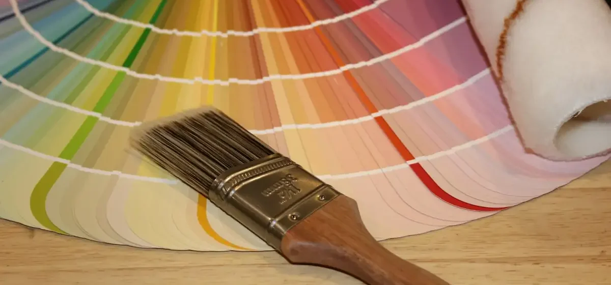 Paint colour fan deck beside a brush and roller sleeve