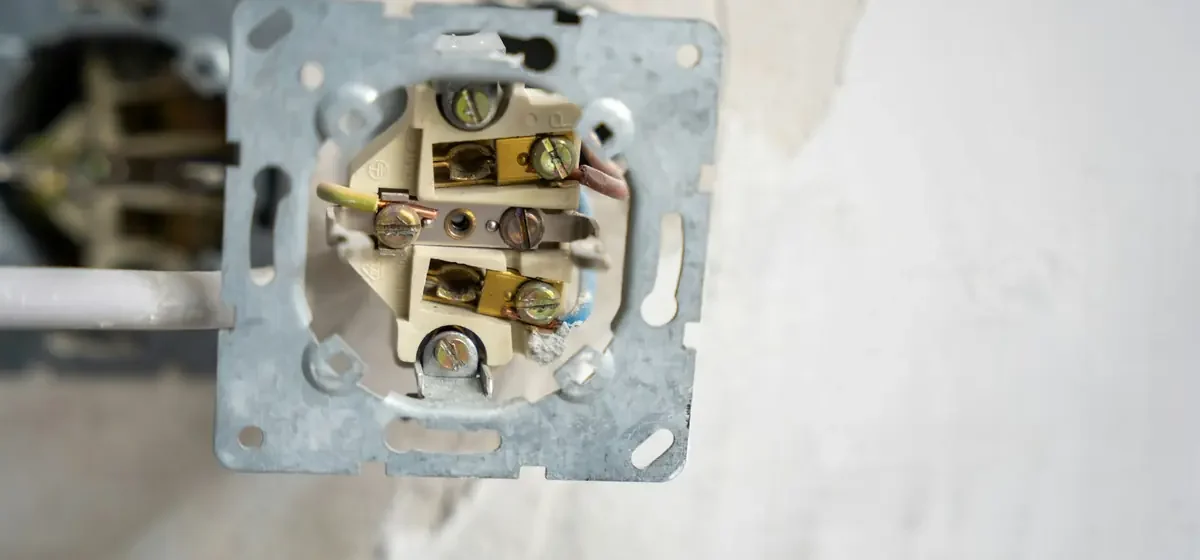 Opened wall socket showing coloured wiring and terminals