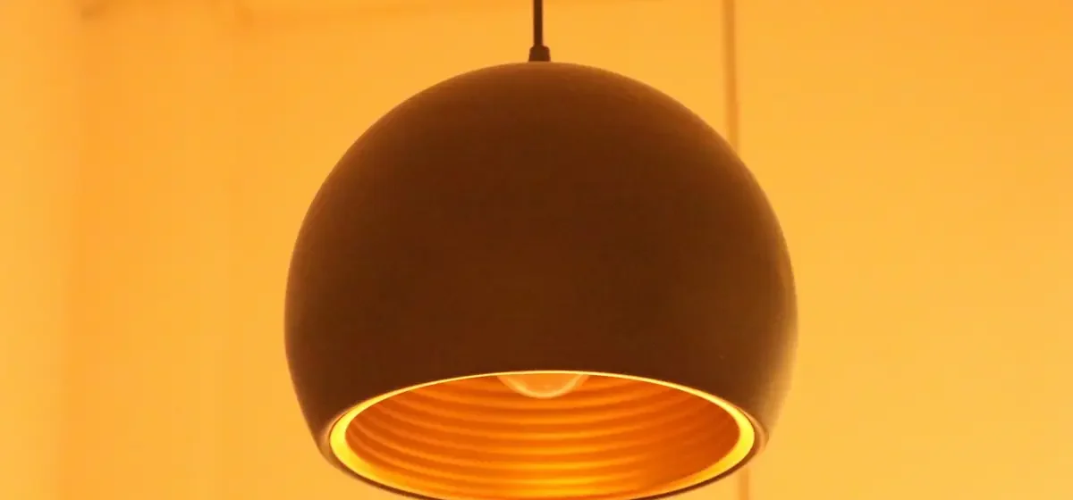 Lit black pendant lamp hanging in a room