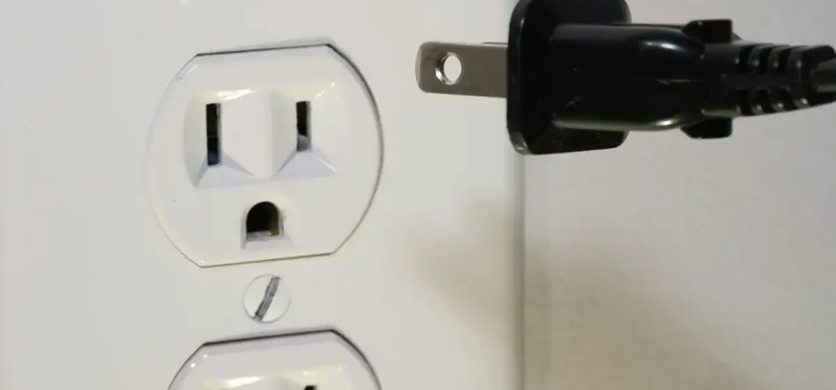 Black plug held beside a white double wall socket