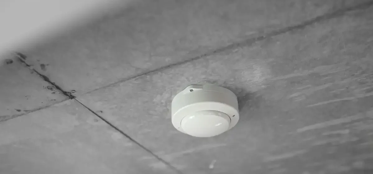 White smoke alarm fitted to a concrete ceiling