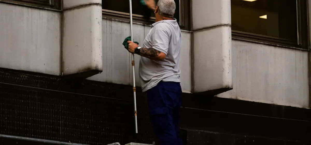 Person cleaning a window with a long-handled squeegee outside