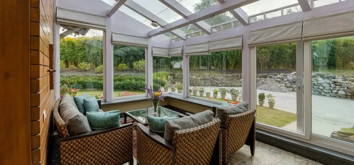 Glazed conservatory with wicker chairs looking onto a garden
