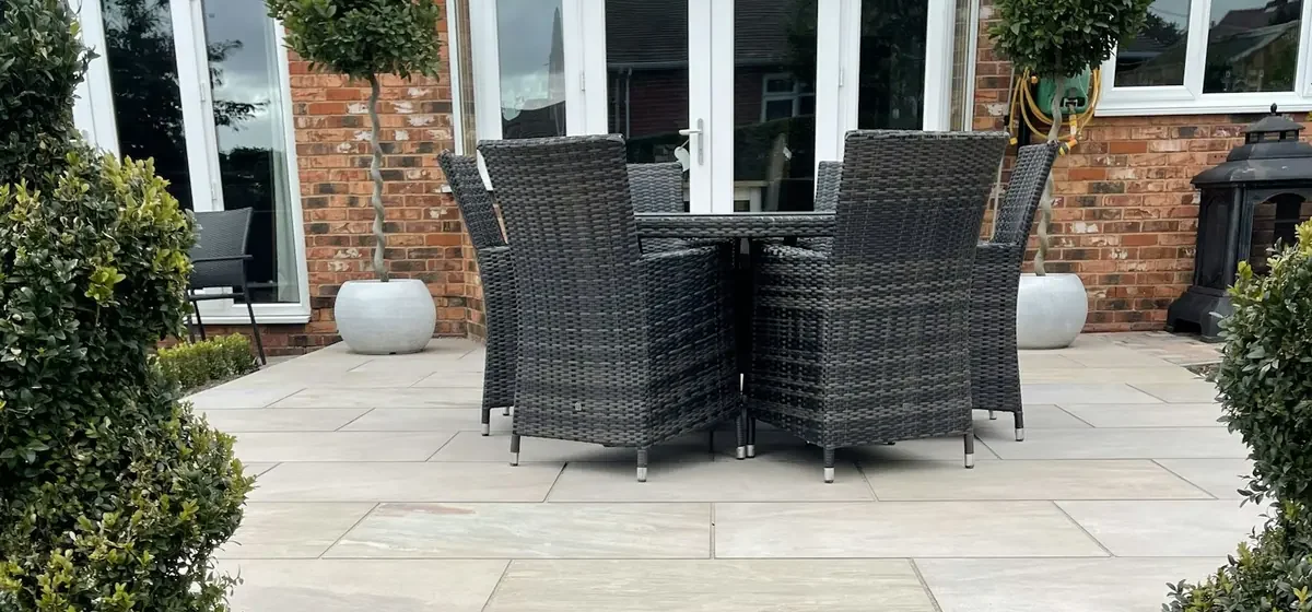 Paved back garden patio with table, chairs and potted plants
