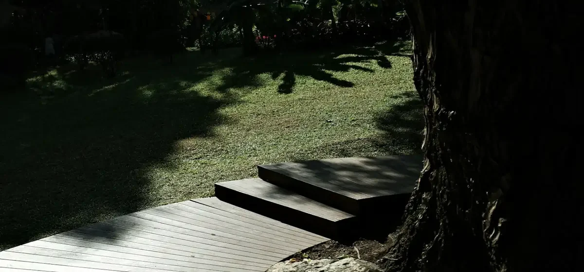 Wooden garden decking with steps down to a lawn