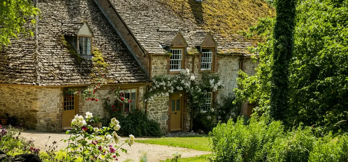 Stone cottage surrounded by a leafy planted garden