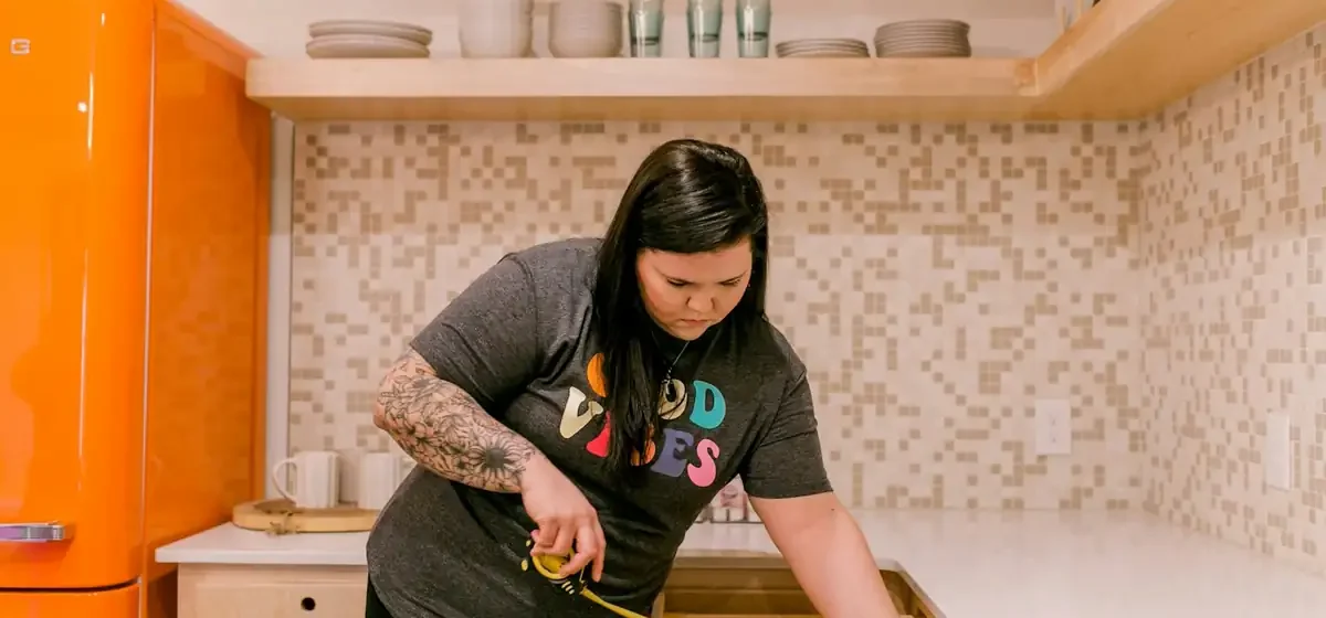 Woman measuring a kitchen drawer with a tape measure