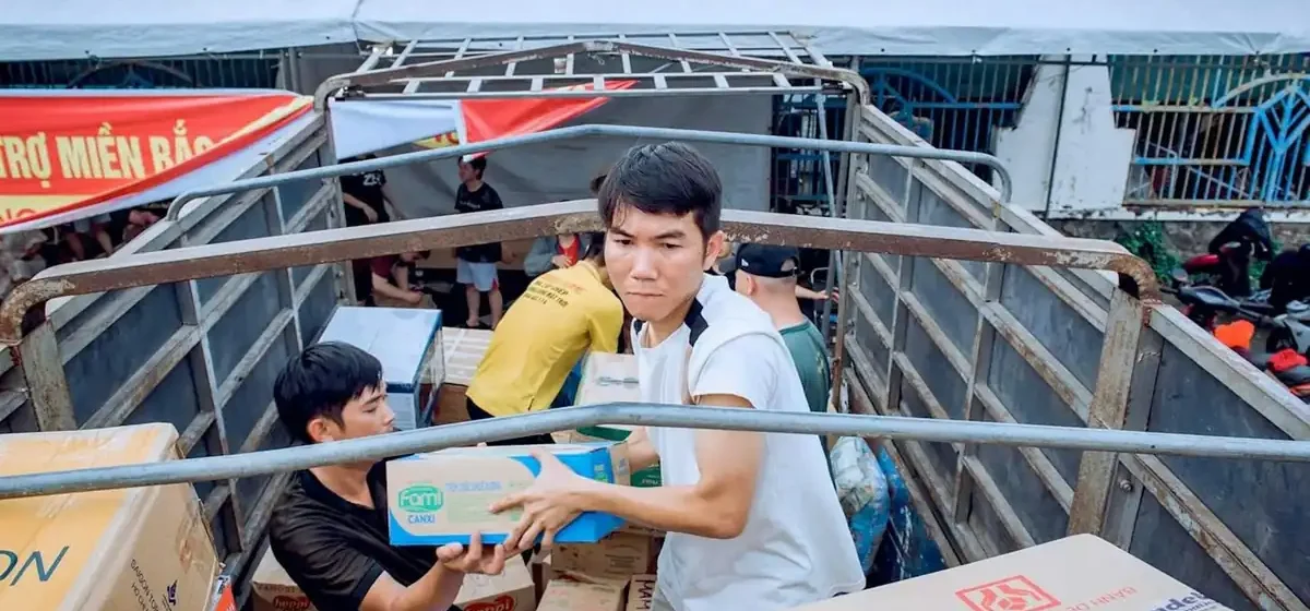 Two men loading cardboard boxes into the back of a truck