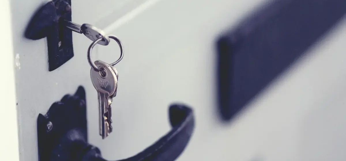 Key left in the lock of a white door with black handle