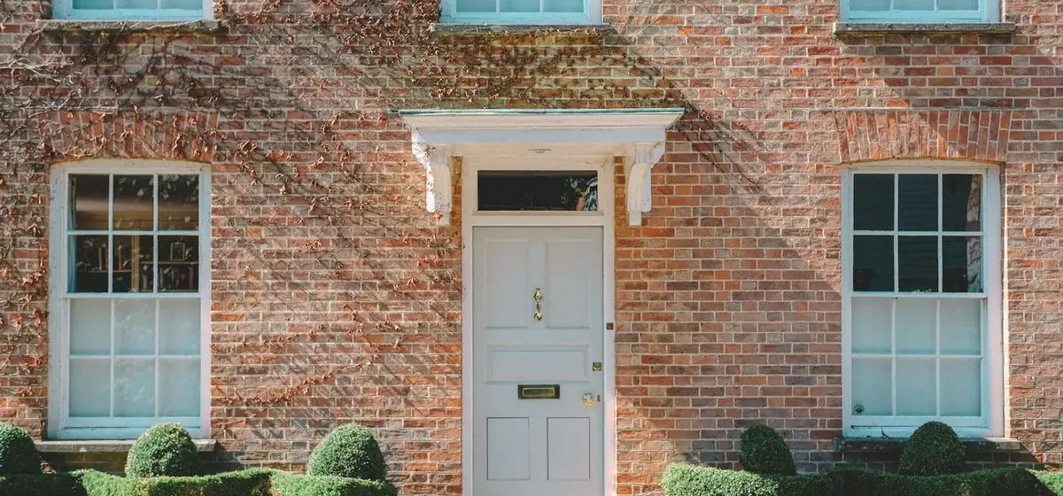 White wooden front door set in a brown brick house
